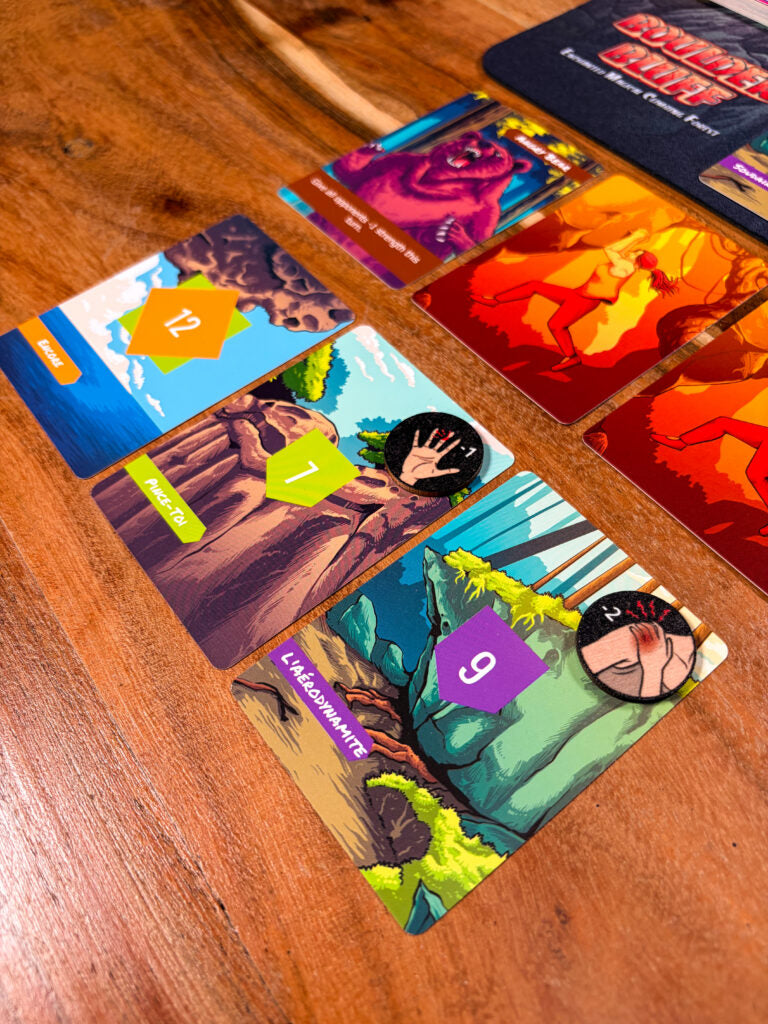 Close-up of Boulder Bluff illustrated route and climbing cards on a wooden table